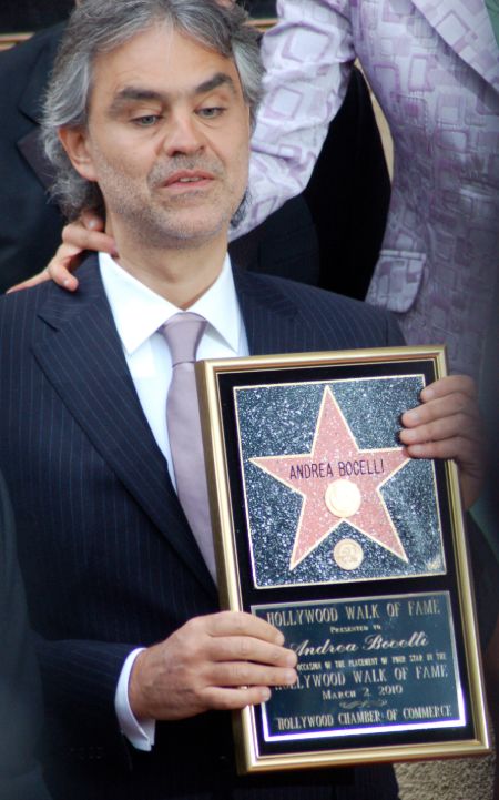 Andrea Bocelli in a black suit poses a picture.